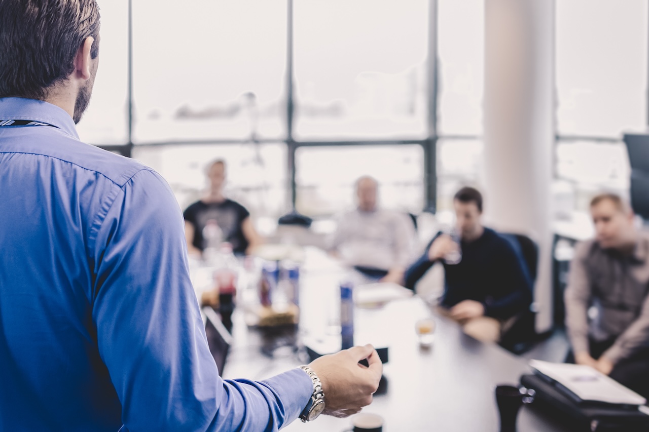 Business man making a presentation at office. Business executive delivering a presentation to his colleagues during meeting or in-house business training, explaining business plans to his employees.